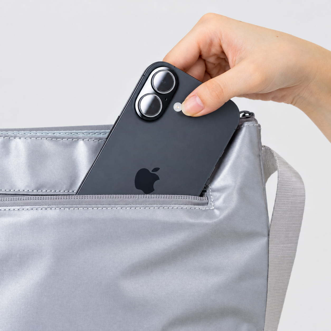 サポッシュ前面の浅型ポケットにスマートフォンを出し入れする様子